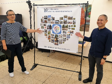 Foto: Martin Heß – Gudrun Heß und Beisitzer Kar-Hong Lau stellen ein Plakat mit Fotos der vom Verein bereits umgesetzten Projekte vor.